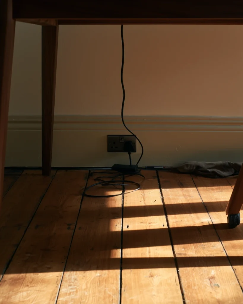 Floor level view under a desk showing the wall socket and single cable run, the first thing to check in a home office setup