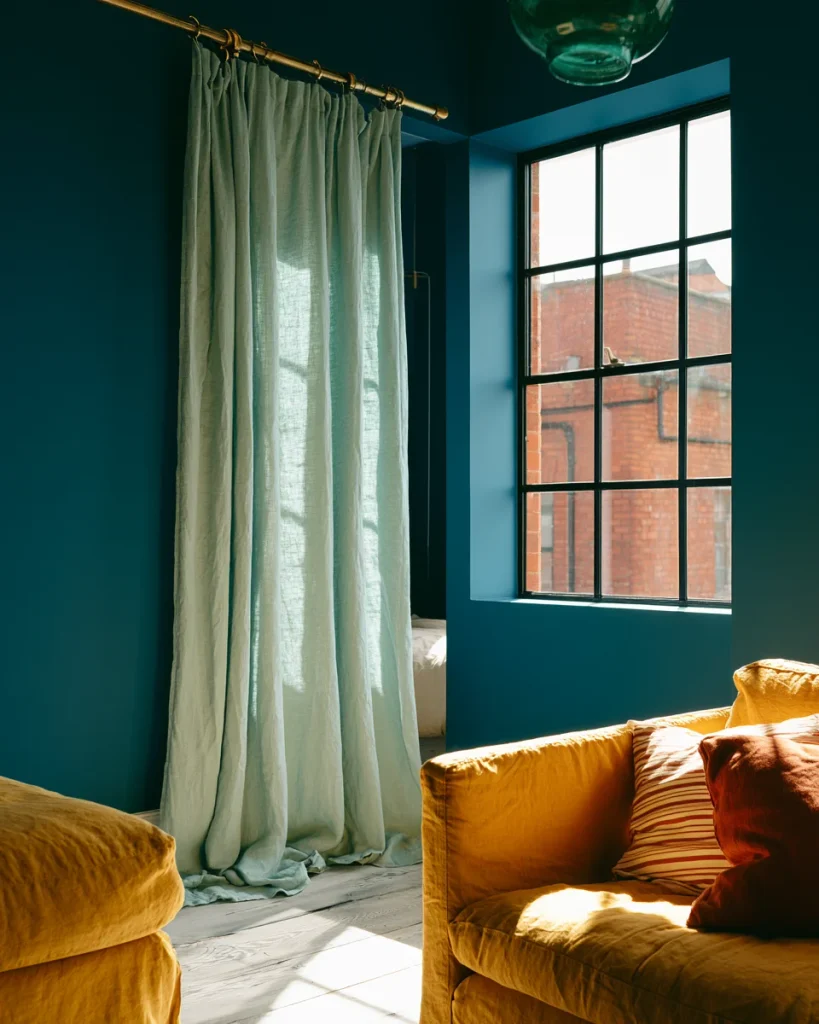 Linen curtain on a ceiling track drawn halfway across a studio, letting daylight through