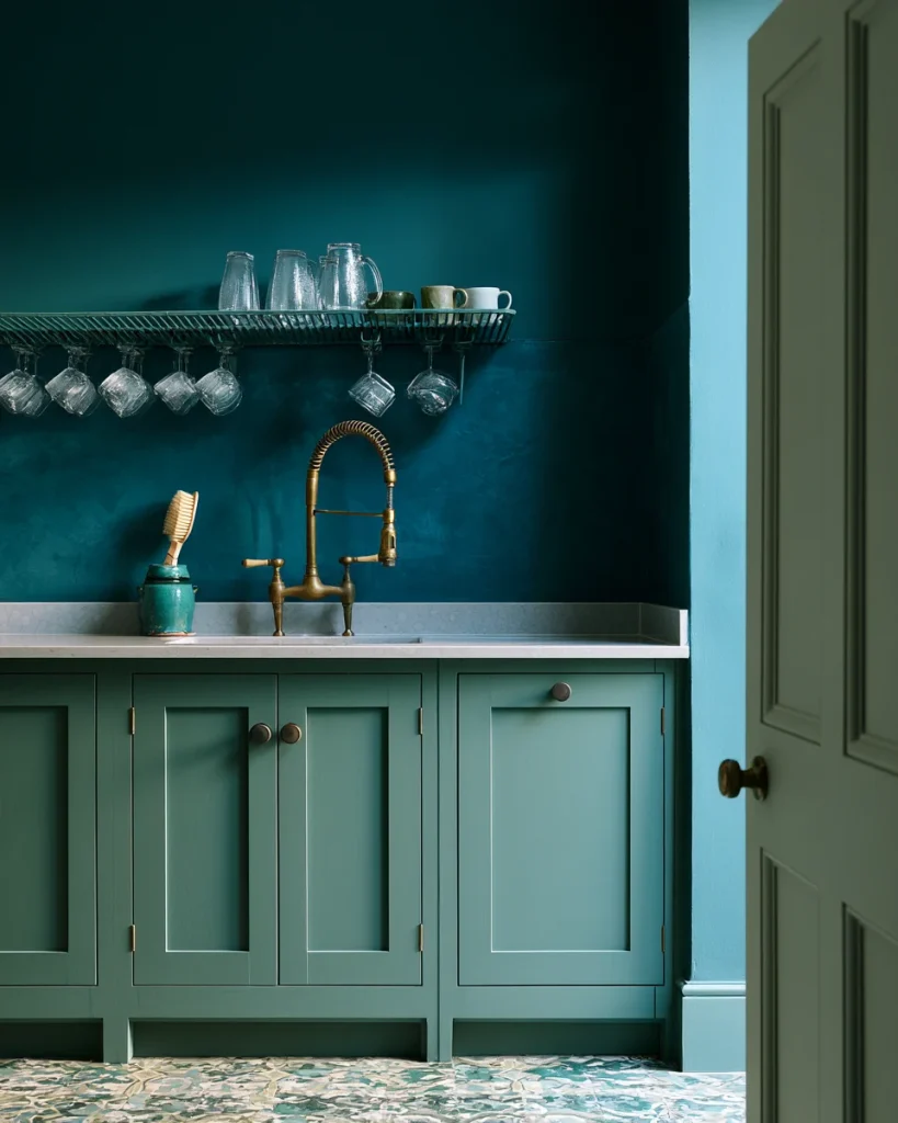 A slatted wire shelf above a kitchen sink holding upturned glasses and mugs, clearing the tap at full swing.
