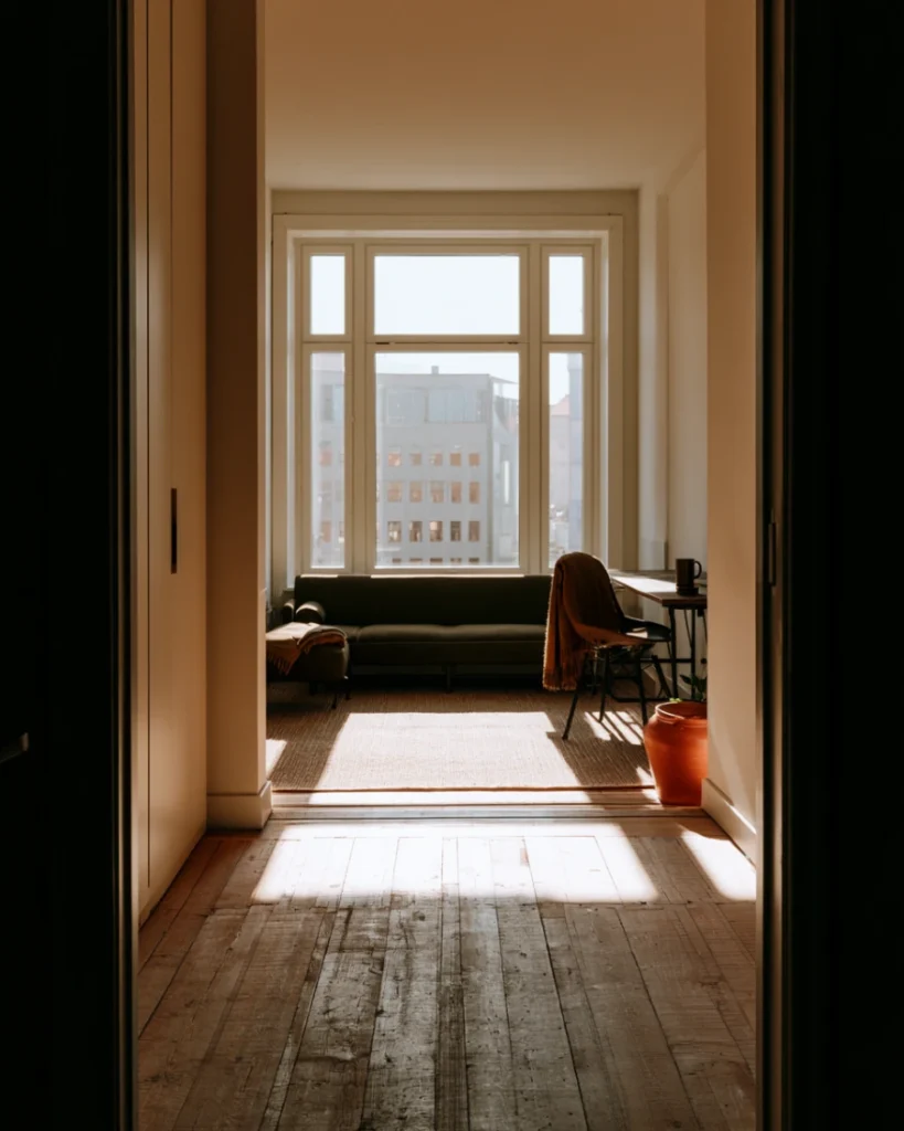 Studio with a full window wall, everything near the glass kept low so the light reaches the room