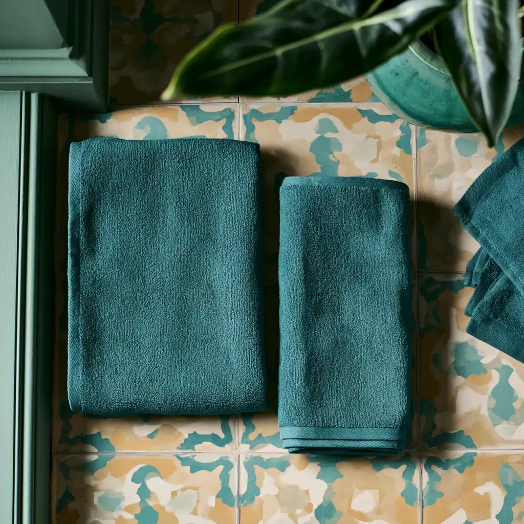 Overhead view of the same towel folded two ways, one wide and flat beside one narrow and thick, showing that the fabric volume does not change.