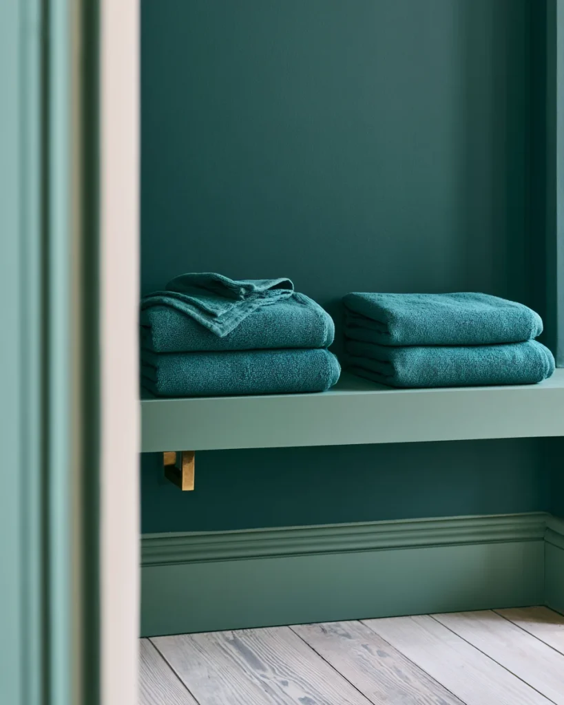 A shallow ten inch shelf holding towels folded to sit flush with the front edge, with nothing projecting past the shelf line.